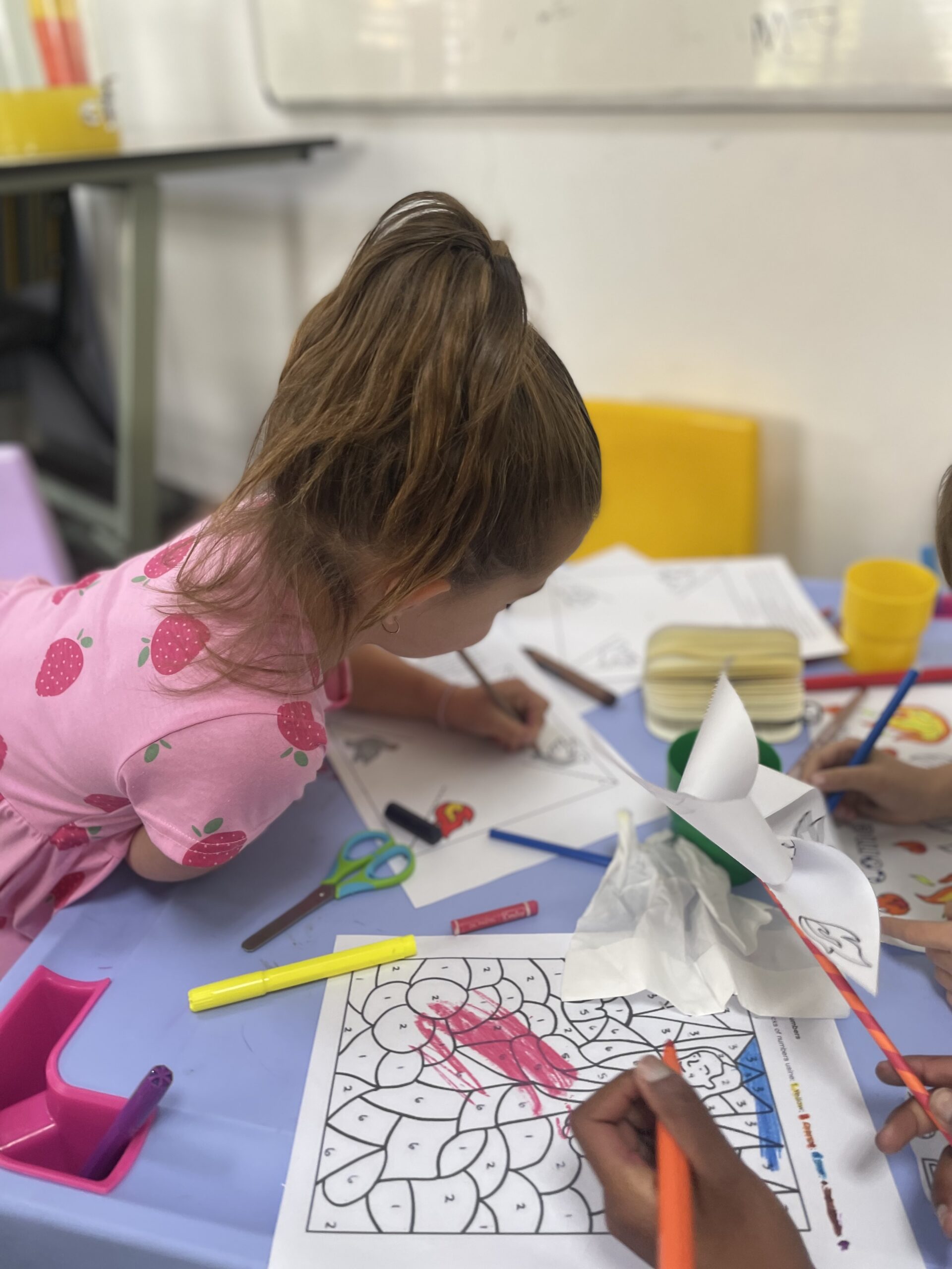 Kings Kidz girl in strawberry shirt focused on Bible craft