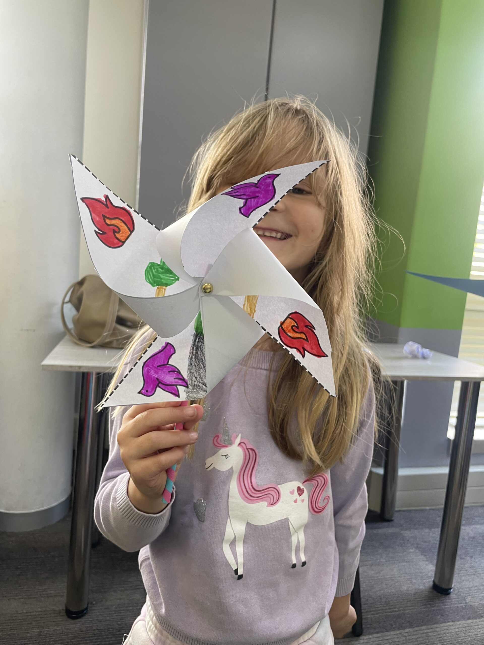 Girl holding pinwheel craft dove and flame